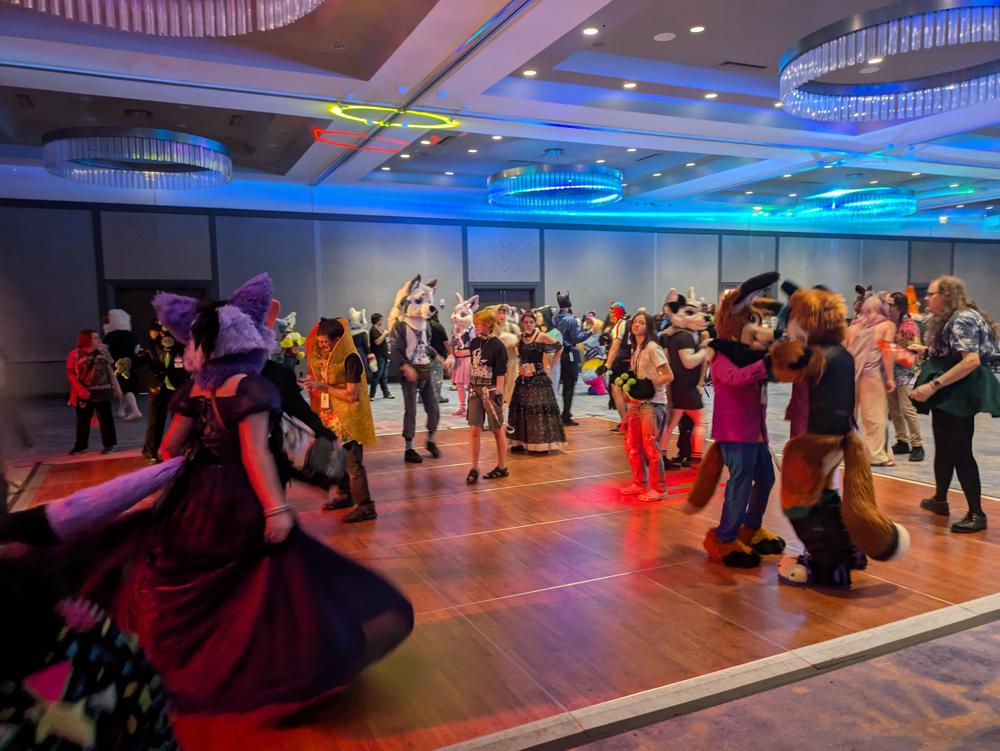 People dancing on a dance floor, many of whom wearing fursuits